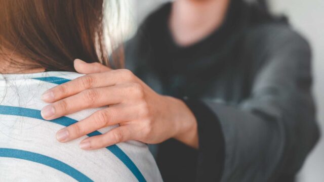 A close-up of a hand on a person's shoulder.