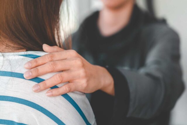 A close-up of a hand on a person's shoulder.