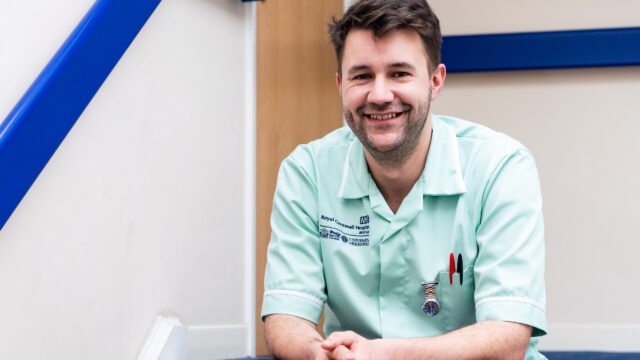 A student nurse sits on a step smiling.