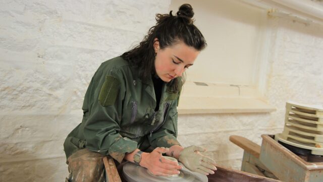A student creating pottery at a pottery wheel.