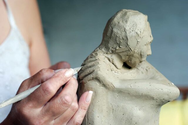 A close-up of a person carving a sculpture from clay.