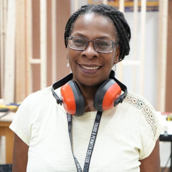 Maria wears ear defenders around her neck and is wearing a student lanyard.