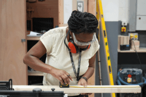 Paola Mara in construction gear and doing woodwork