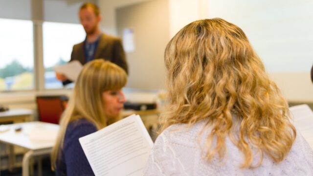 The back of a person's head and over their shoulder as they are looking at a document.