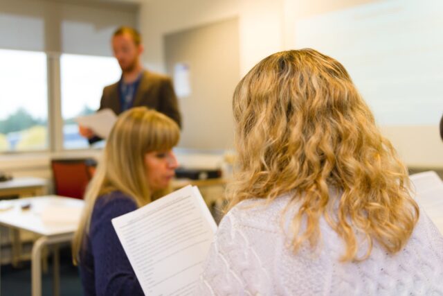 The back of a person's head and over their shoulder as they are looking at a document.
