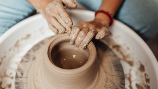 A young woman works in a clay pots workshop.