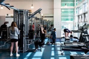 A photo of the College's gym. There are students stretching and using various equipment around the gym.