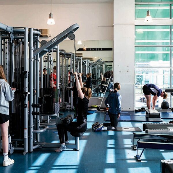 A photo of the College's gym. There are students stretching and using various equipment around the gym.