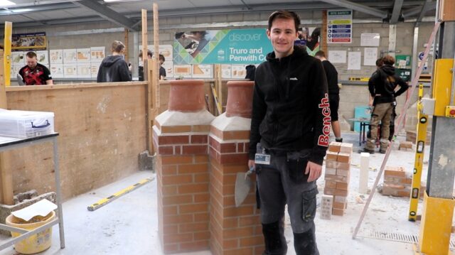 Roman stands with two chimneys that have just been made behind him. He has a trowel in his hand.