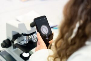 A picture taken over the shoulder of a student. They have a picture of a cell on their mobile phone.