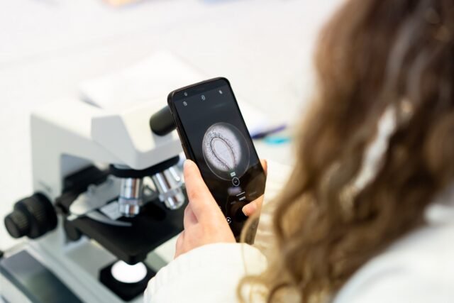 A picture taken over the shoulder of a student. They have a picture of a cell on their mobile phone.