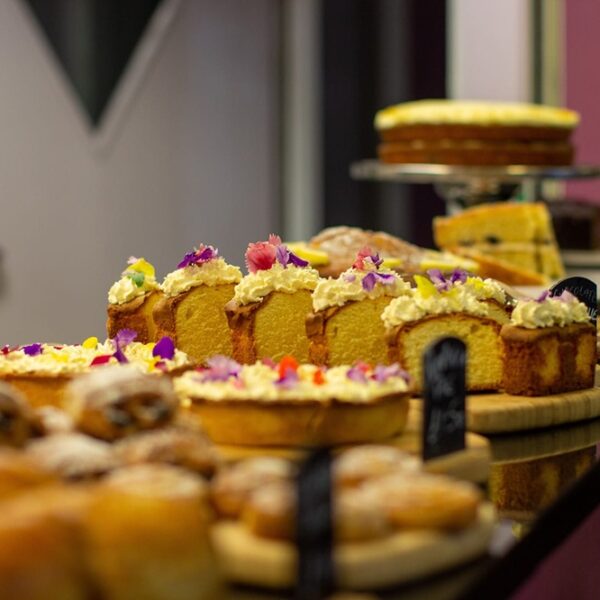A close up picture of cake on a counter top. The cake has cream on top and small flowers.