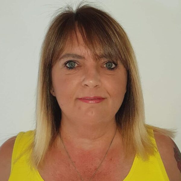 A photo of Stef, she is wearing a yellow top with a silver neckalce.
