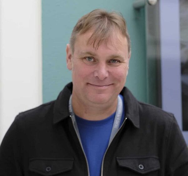 A photo of Tim Moody, he is wearing a dark jacket and is smiling at the camera.