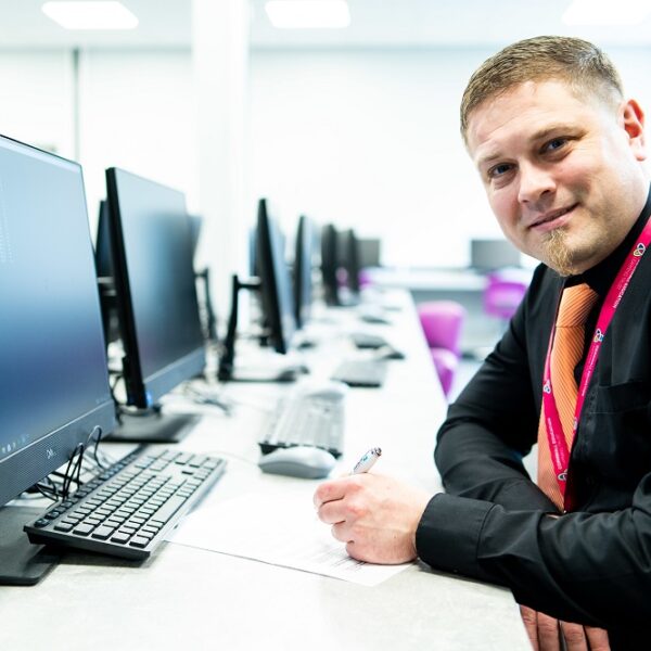 An apprentice sits at a computer table filling out paperwork.