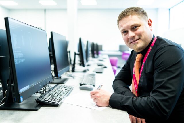 An apprentice sits at a computer table filling out paperwork.