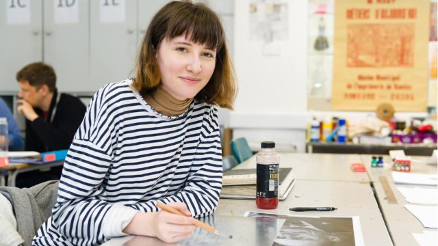 A student in an art room holding a brush.