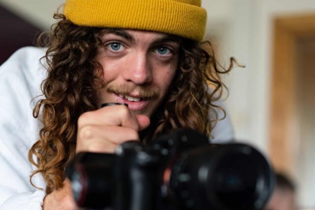 A student looks up from a camera wearing a yellow beanie.