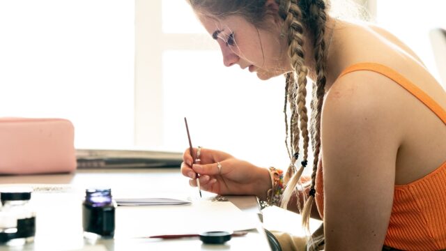 A student paiting in a brightly lit room.