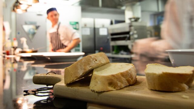 A close up of sliced bread on a chopping board in a professional kitchen.
