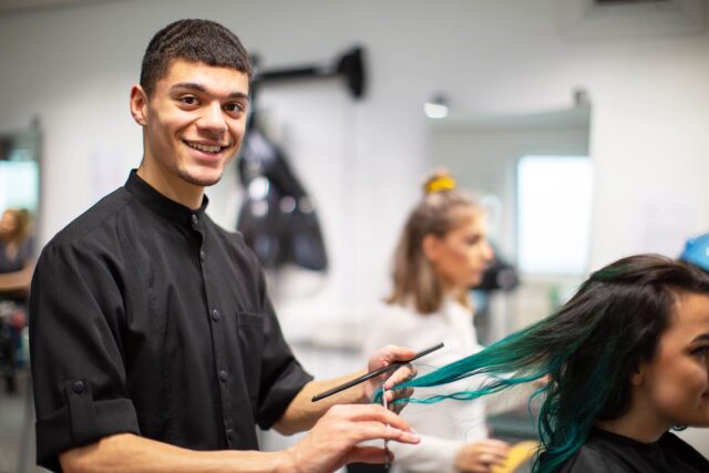 A male hairdresser cutting a client's hair.