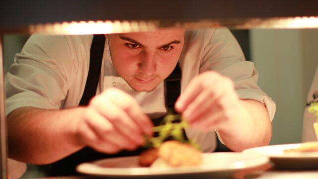 A chef putting the finishing touch on a dish.