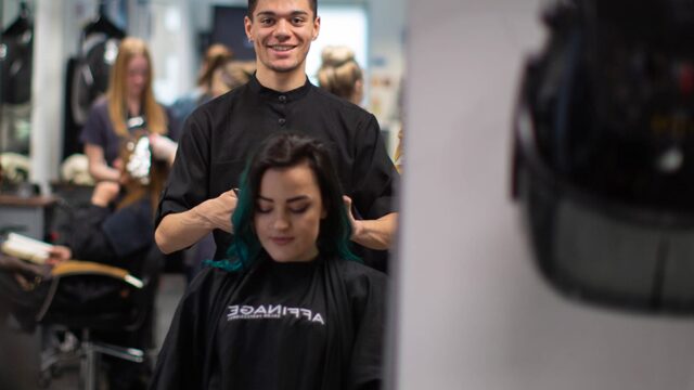 A student working on the hair of a client in a professional salon.