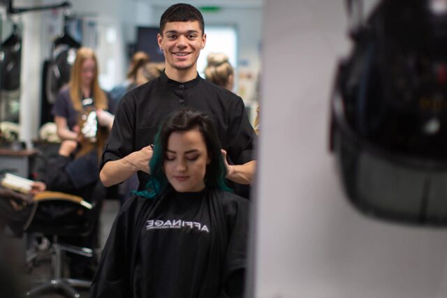 A student working on the hair of a client in a professional salon.