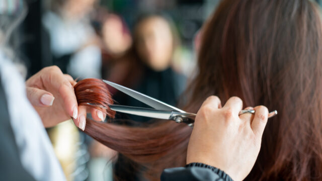 Close up of unrecognisable hairdresser cutting a female customer's hair.