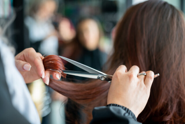 Close up of unrecognisable hairdresser cutting a female customer's hair.
