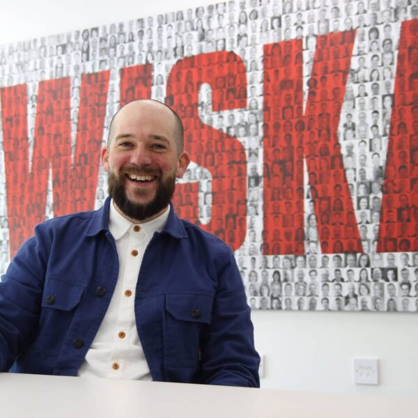 Elliott sat at a white table with a large WISKA sign behind him.