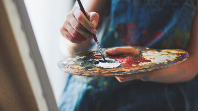 An artist holding a palette and a paintbrush.