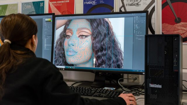 A student using photoshop on an image of a women on a computer.