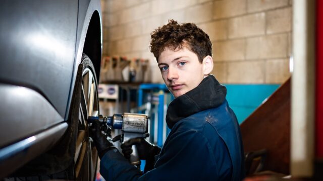 A student working on a car's wheels.