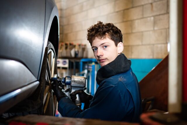 A student working on a car's wheels.
