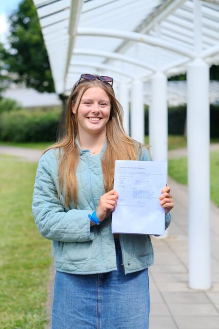 Bella holds up her results and smiles.
