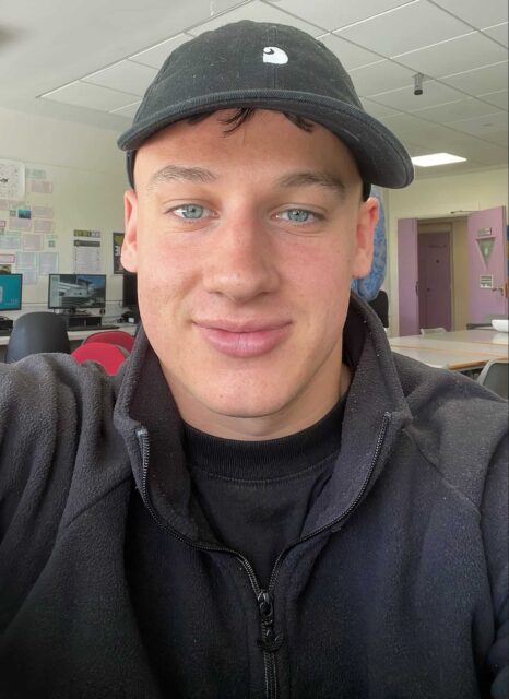 Cam is wearing a dark fleece and baseball cap.