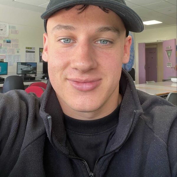 Cam is wearing a dark fleece and baseball cap.