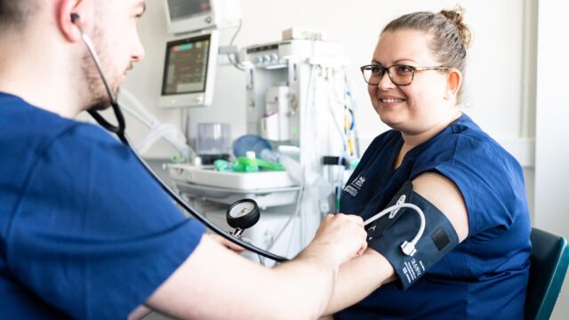 Two health students practice using a blood pressure monitor.