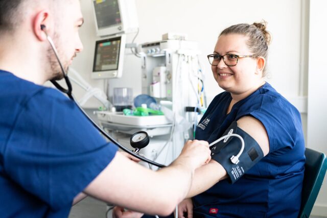 Two health students practice using a blood pressure monitor.