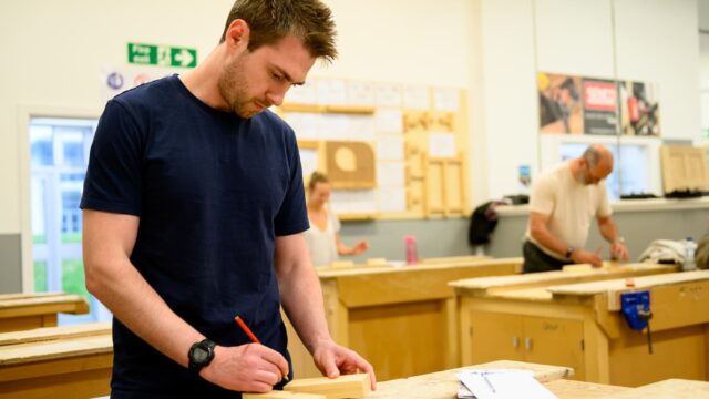 A person making markings on blocks of wood.
