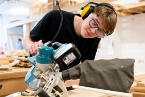A student uses an electric saw in a workshop.