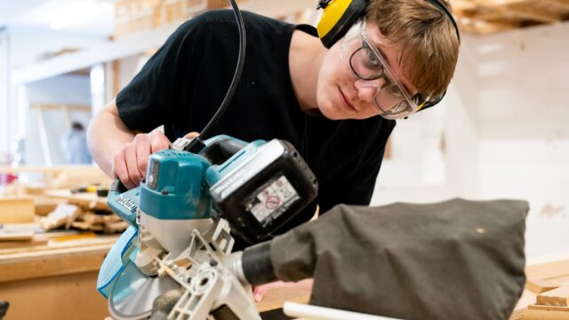 A student uses an electric saw in a workshop.