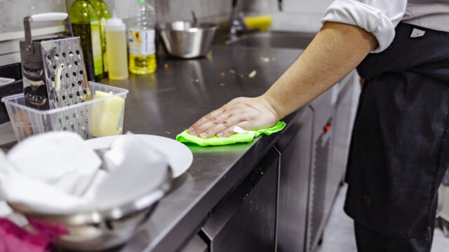 A hand wipes down a kitchen worktop.
