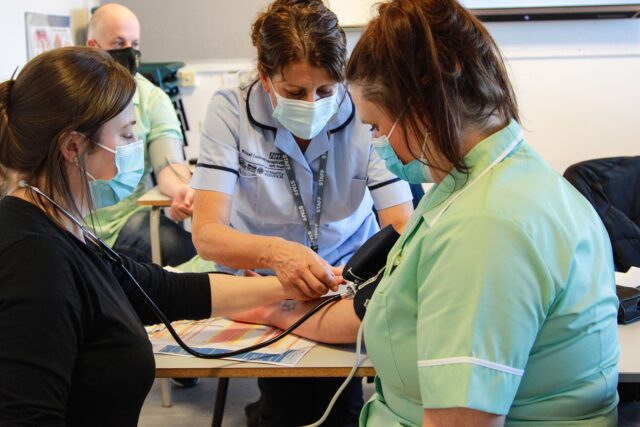 Students and staff use a stethoscope together.