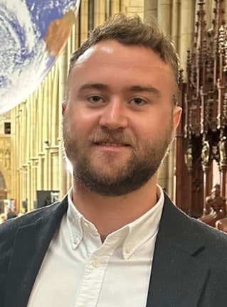 A photo of Olaf Marshall-Whitley, he is stood inside the Truro Cathedral and is wearing a suit.
