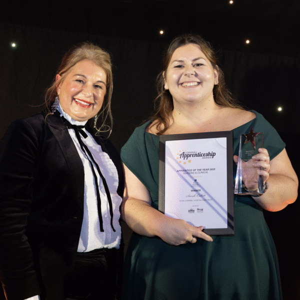 Sarah holds her trophy and certificate and is accompanied by another woman.