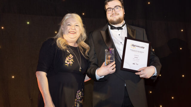 Piers Smith, Winner of the Achiever of the Year category holds his trophy and certificate on stage with Julie-Anne Sunderland from category sponsors Wildanet