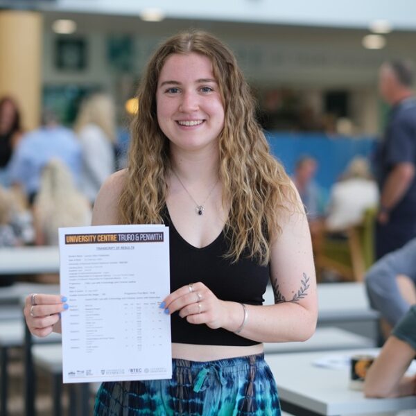 A photo of Lauren, she is holding her results up and she is wearing a black vest top. She has long blonde hair.