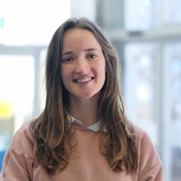 A photo of Lowenna, she has long brown hair and is wearing a peach jumper with a white collar.